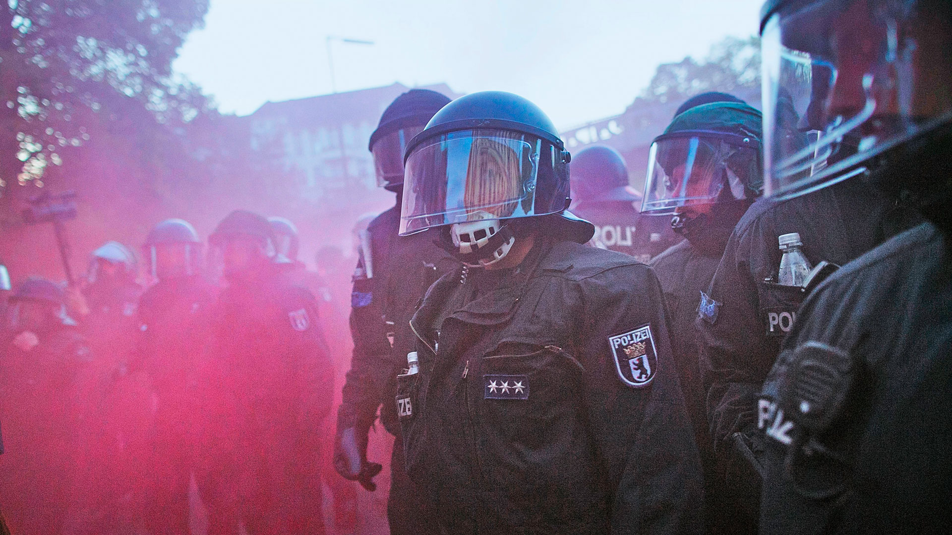 Polizisten in Vollmontur mit pinkem Nebel
